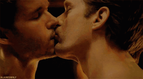 two men are kissing with their eyes closed in a close up of their mouths .