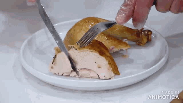 a person is cutting a piece of chicken with a knife and fork