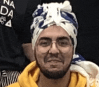 a man with a beard and glasses is wearing a turban on his head .