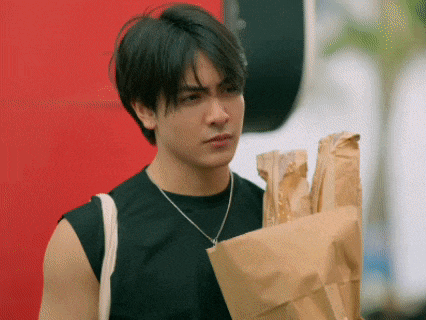 a man in a black tank top is holding a brown bag