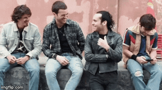 a group of young men are sitting next to each other and laughing