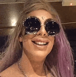 a close up of a woman wearing sunglasses and a necklace .