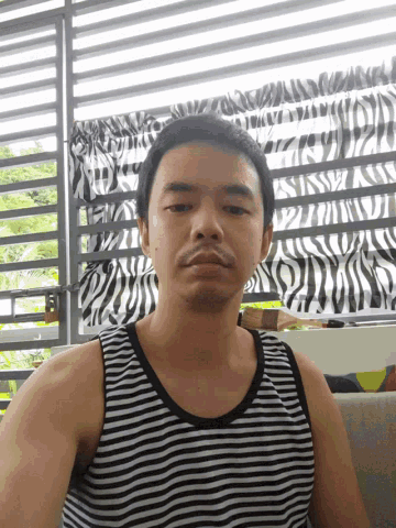 a man wearing a black and white striped tank top is standing in front of a zebra print curtain