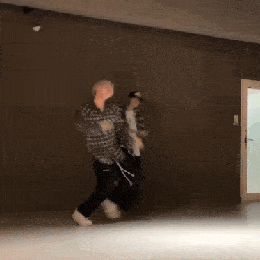 a couple of people are dancing in a room with a door in the background .