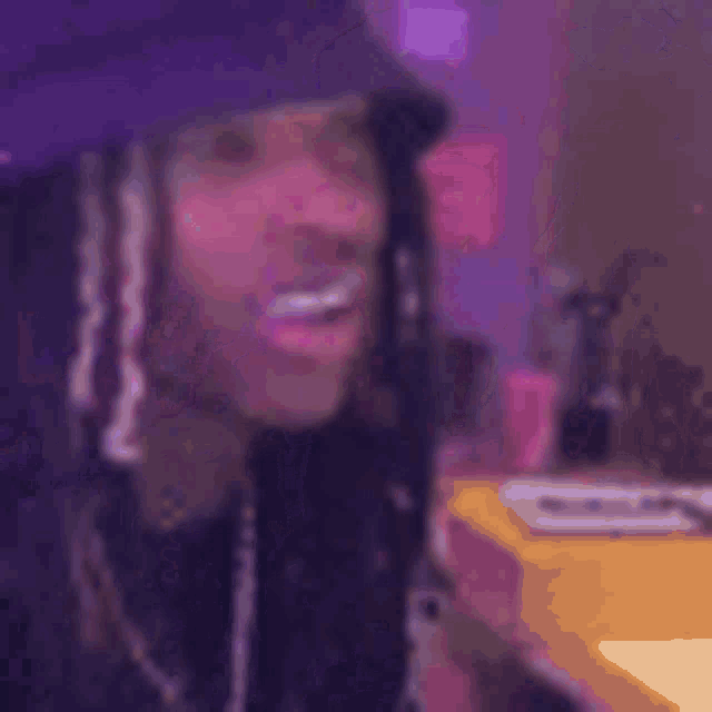 a close up of a person wearing a purple hat and dreadlocks .