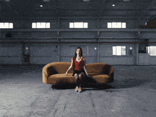 a woman in a red dress sits on a couch in a dark room