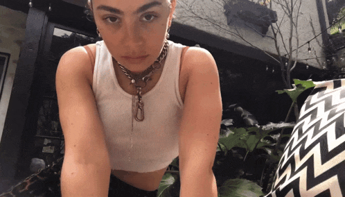 a woman wearing a white tank top and a necklace