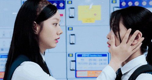 two girls are touching each other 's faces in front of a sign that says ' locker room '
