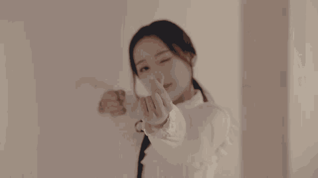 a woman in a black dress and white cuffs holds a green apple