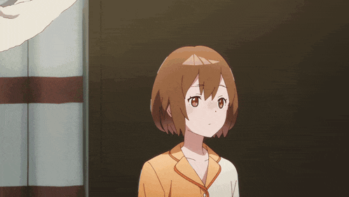 a girl with short brown hair is standing in front of a wall