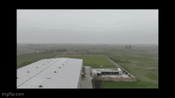 an aerial view of a large white building in the middle of a field on a cloudy day