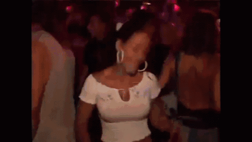 a woman in a white top is dancing in a crowd