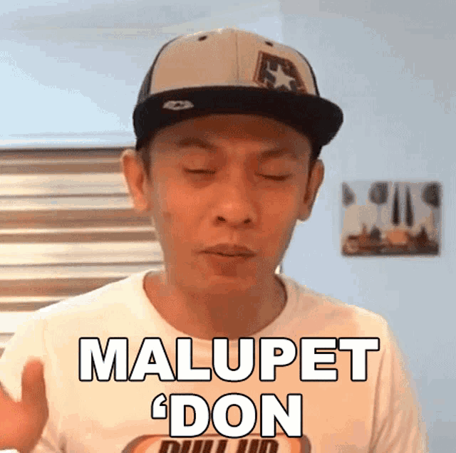 a man wearing a hat and a t-shirt that says malupet don