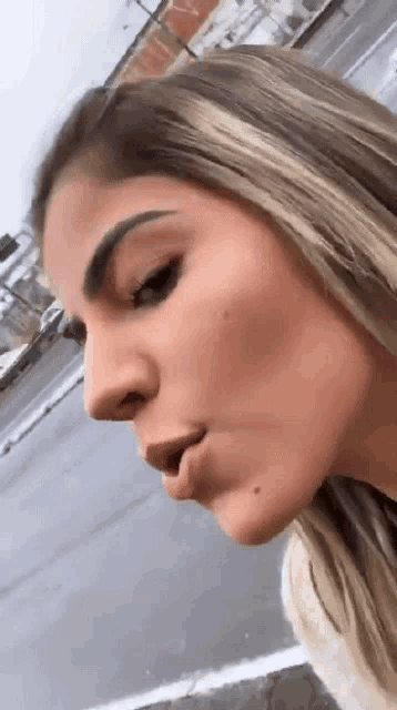a close up of a woman 's face with her mouth open and a building in the background .