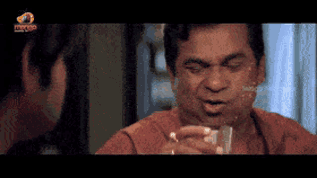 a man in a red shirt is holding a glass of water in his hand