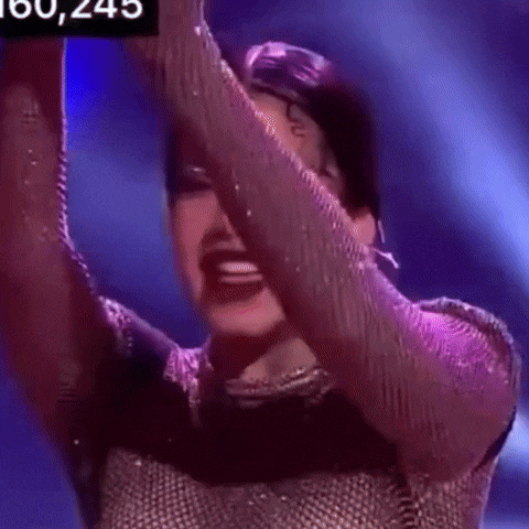 a woman in a purple dress is dancing on a stage with her arms in the air .