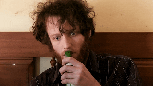a man with a beard is holding a bottle in his hand
