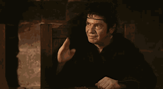 a man with a crown on his head is sitting at a table looking at something
