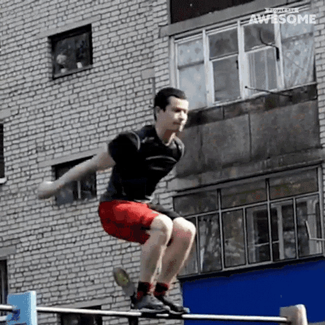 a man is doing a squat on a bar in front of a building .