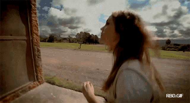 a gif of a woman looking out of a window with the words rbd.gif below it