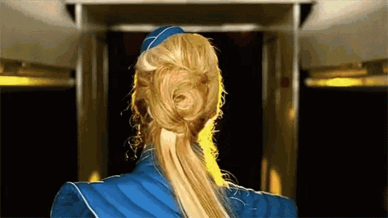 a blonde woman in a blue uniform has her hair in a ponytail