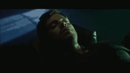 a man is laying in a dark room with a green background