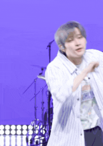 a man in a striped shirt is dancing on a stage in front of a drum set