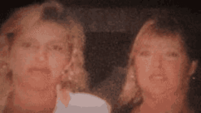 two women are posing for a picture together and looking at the camera .