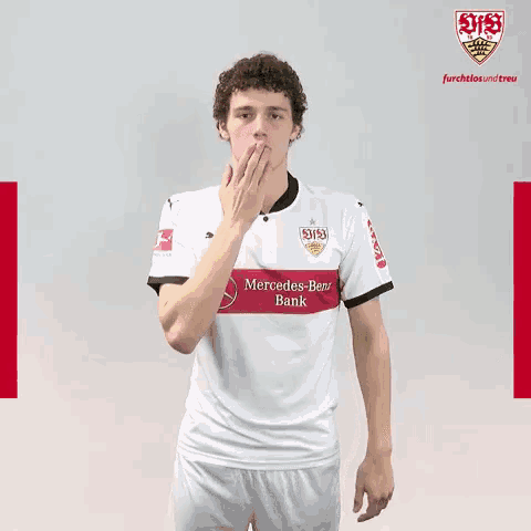 a man in a white mercedes benz bank shirt blows a kiss