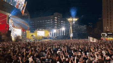 a large crowd of people are gathered at a concert with a large cross in the middle