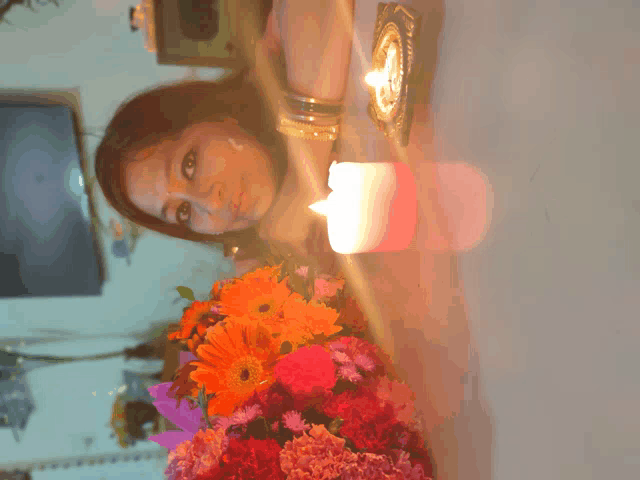 a woman sitting at a table with flowers and a candle
