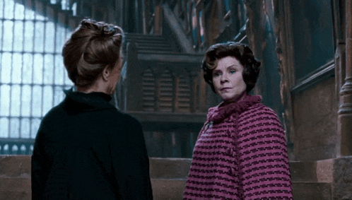 two women are standing next to each other and one is wearing a pink sweater
