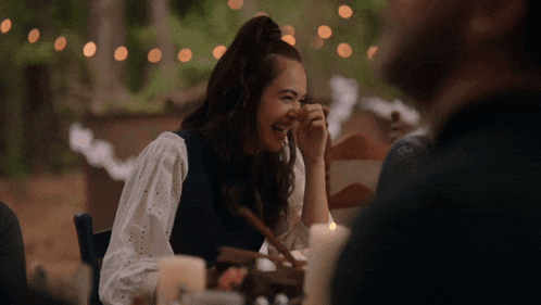 a woman is laughing while sitting at a table with a man