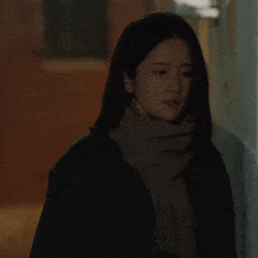 a woman wearing a scarf and a jacket with the letter a on the front