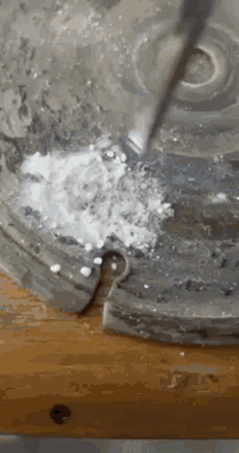 a spoon is being poured into a bowl of powder on a table .