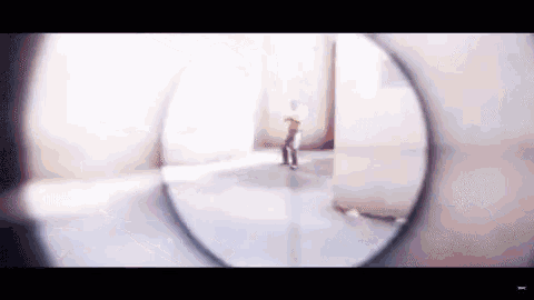 a person is standing in a room looking through a sniper scope .