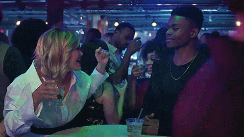 a man and a woman are sitting at a table with drinks in their hands