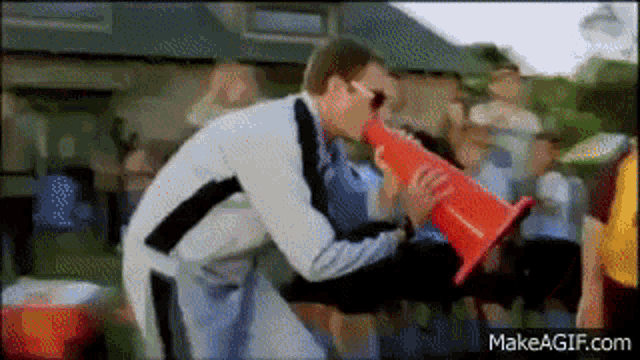 a man is holding a red cone in his hand and blowing into it