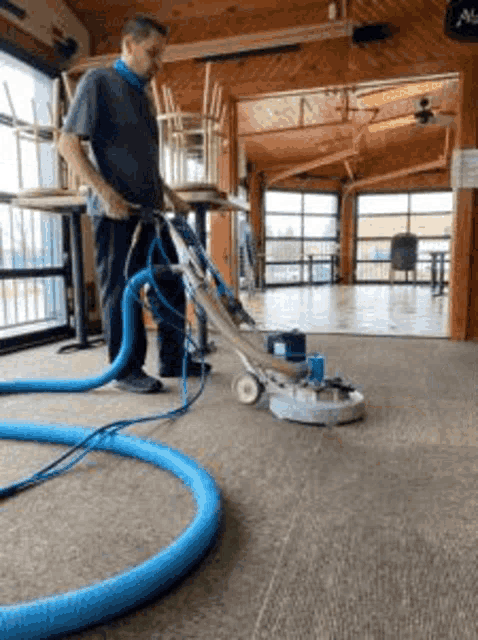 a man is using a vacuum cleaner to clean the carpet in a room .