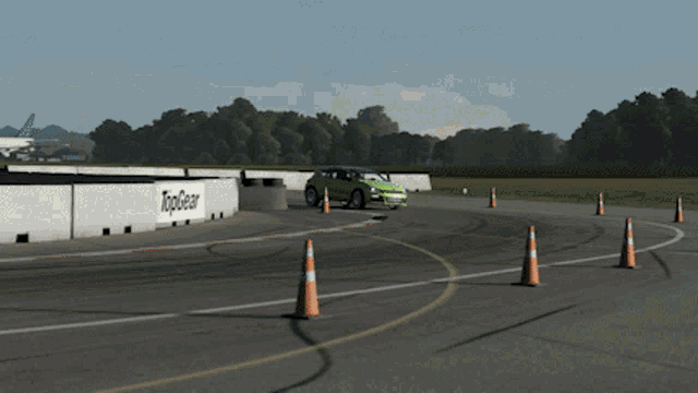 a green car is driving on a track with cones and a sign that says topgear on it
