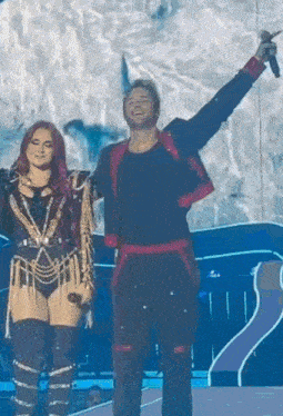 a man and a woman are standing on a stage holding microphones .