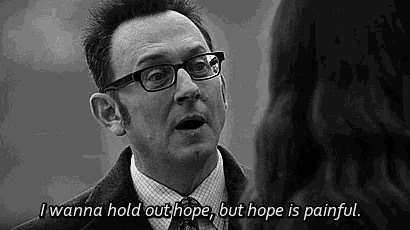 a man with glasses is talking to a woman and saying `` i wanna hold out hope , but hope is painful '' .