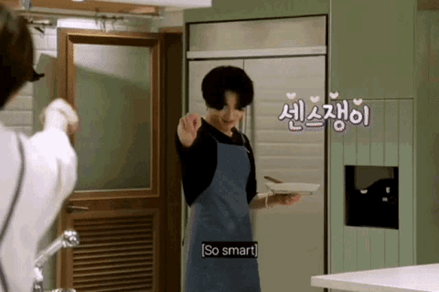 a man in an apron is standing in a kitchen holding a plate and a spoon .