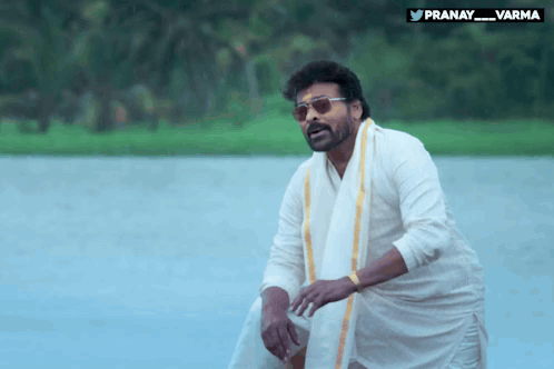 a man standing in front of a body of water with the hashtag pranay_varma on the bottom right