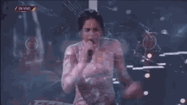 a woman is singing into a microphone while wearing a pink dress .