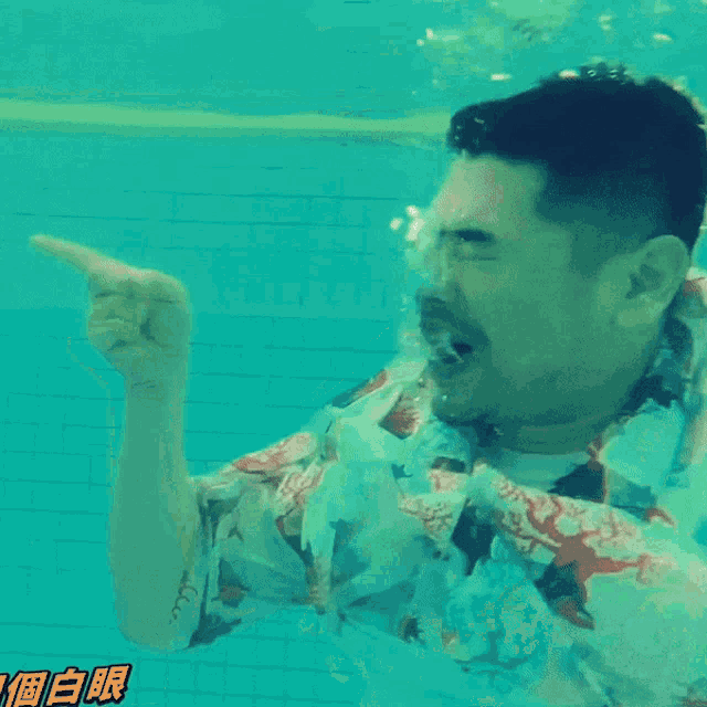 a man in a hawaiian shirt is swimming underwater in a pool