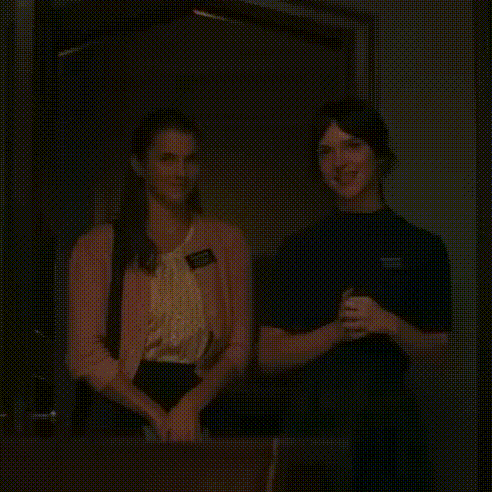 two women are standing next to each other in a dark room