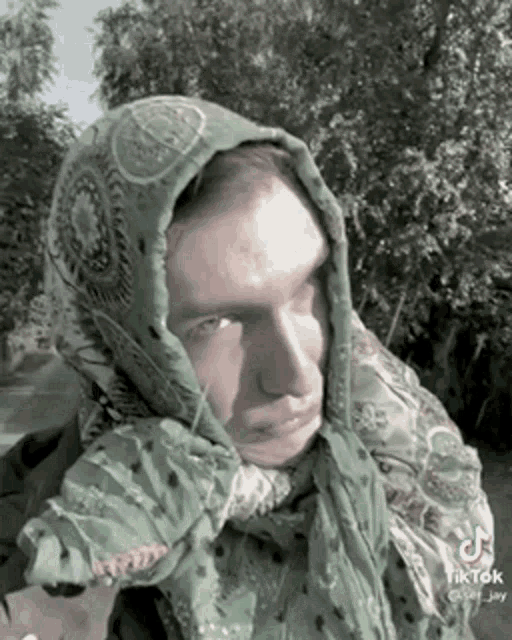 a man wearing a green scarf around his head has tiktok written on the bottom right
