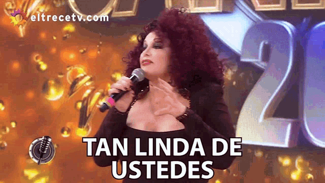 a woman singing into a microphone with the words tan linda de ustedes on the bottom