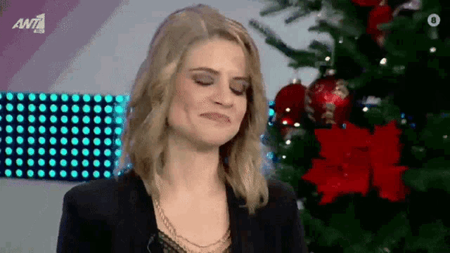 a woman is making a face in front of a christmas tree
